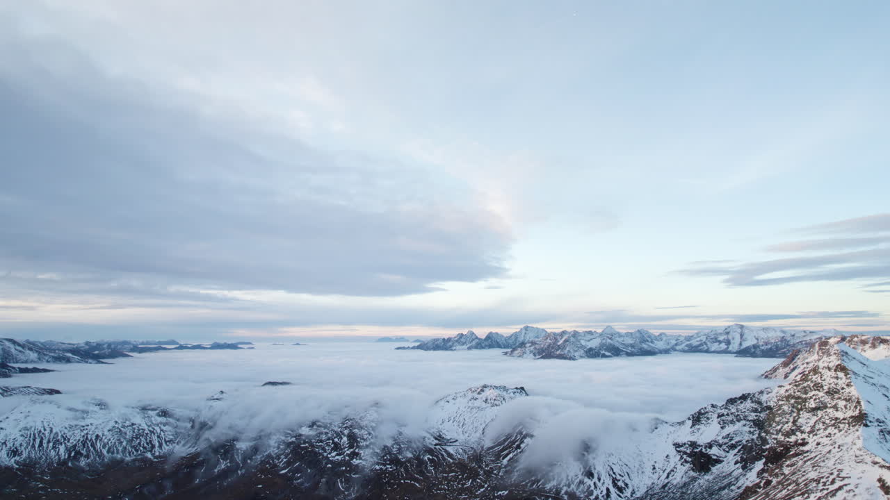오스트리아의 3000m 산의 눈 덮힌 산 위에 구름 층을 드러내는 드론 짐벌 다운