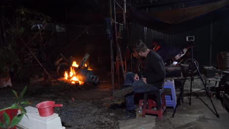 Man-sitting-cautiously-as-old-gas-tank-burning-to-remove-excess-paint