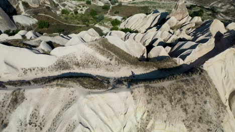 rotating epic cinematic drone shot of a lone man walking a path up a hill in cappadocia, turkey