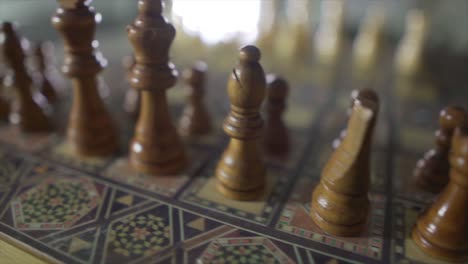 close up pan shot of retro wooden figures of chessboard and sunlight in backdrop