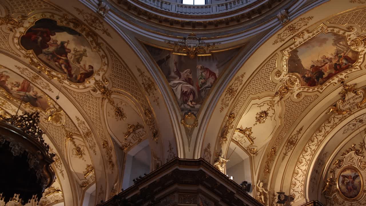 Vista detallada en contrapicado del techo barroco dorado y los frescos magistralmente pintados dentro de la histórica basílica de Bérgamo Alta