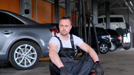 mechanic sitting in a car repair shop