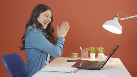 mujer joven mirando la computadora portátil aplaudiendo.