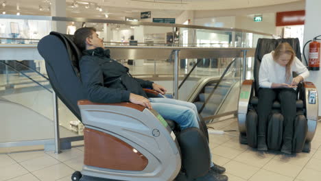 personas en sillas de masaje en el centro comercial