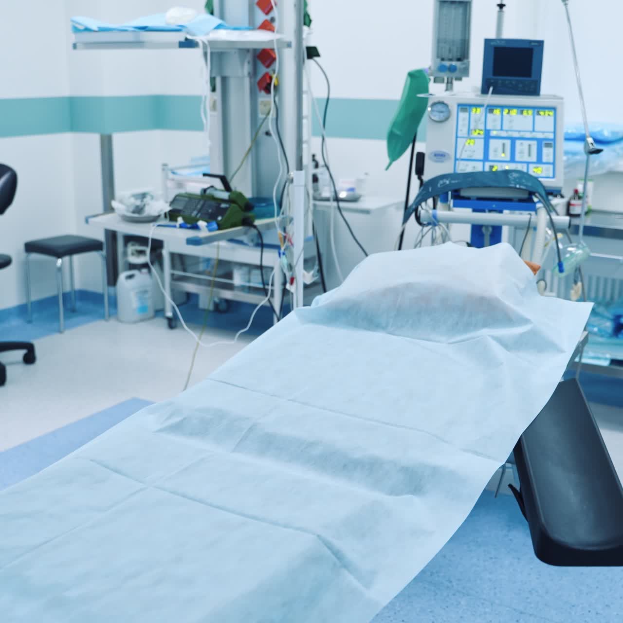 Surgery room with modern equipment. Surgical bed in the centre of the operating theatre and nobody inside. Sterile operating room with advanced equipment.