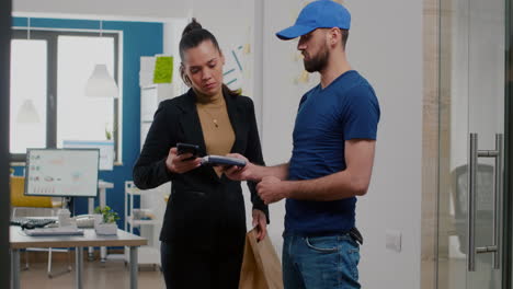 Delivery-man-bringing-takeaway-food-meal-order-to-businesswoman-in-startup-company-office