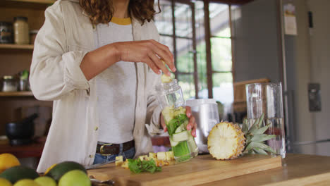 Feliz-Mujer-De-Raza-Mixta-Preparando-Una-Bebida-Saludable-De-Pie-En-La-Cocina-De-La-Cabaña-Sonriendo