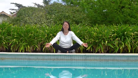 active woman practicing yoga exercise on poolside