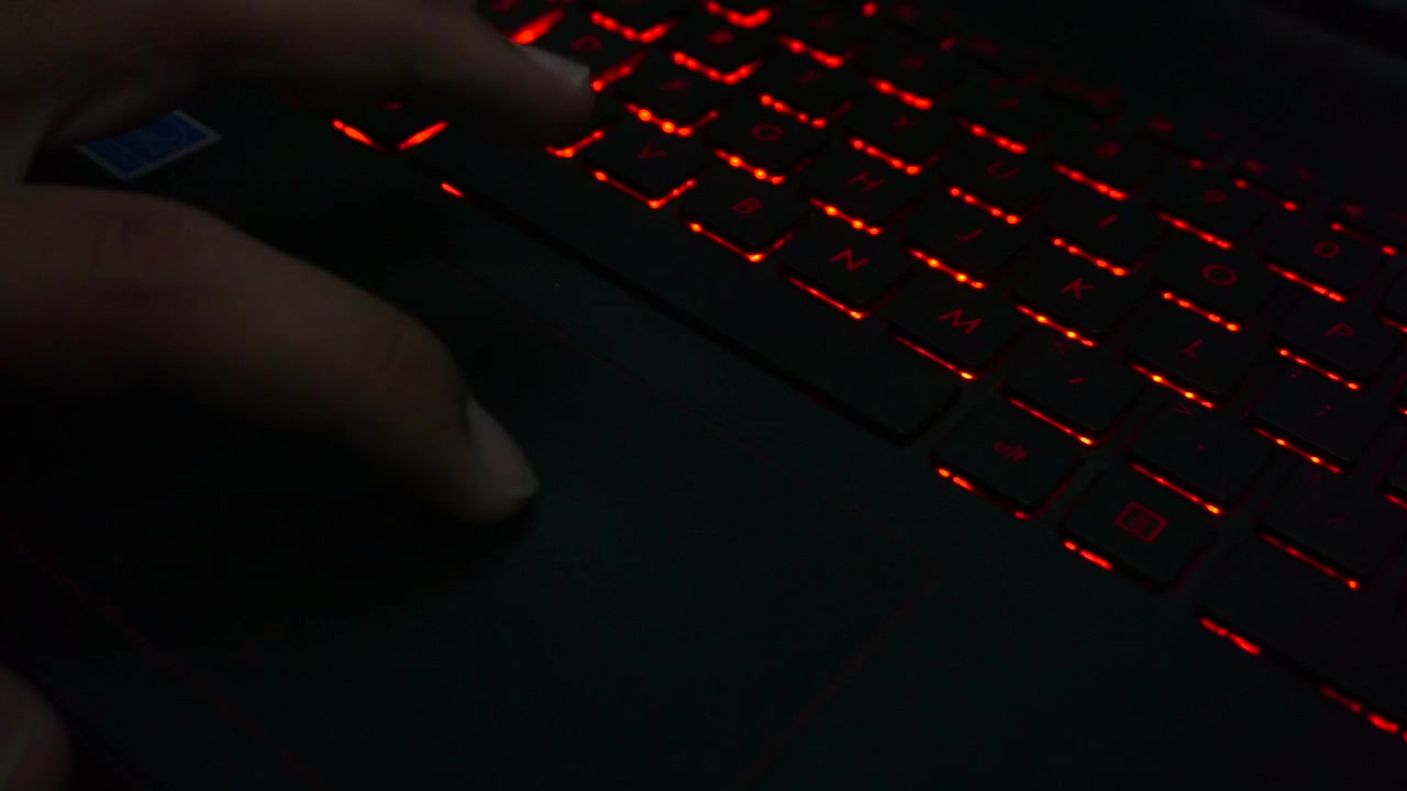 Close up shot of finger make move on the laptop pointer pad with the background of the light from the keyboard