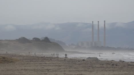 chimeneas o pilas de morro bay en la distancia con gente caminando en la playa