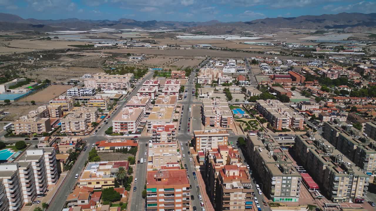 Aerial view of residential districts in Águilas, Murcia, Spain, showing city streets, housing blocks and surrounding dry landscapes under clear Mediterranean skies