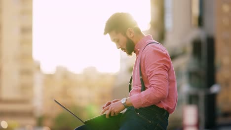 man working on laptop outdoors at sunset