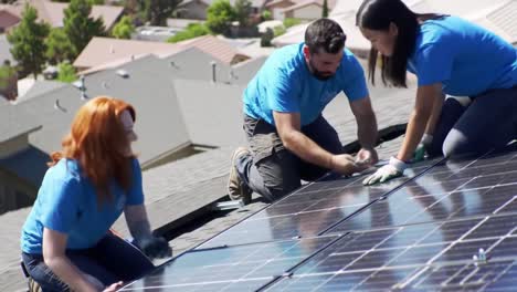 a team of three individuals works diligently installing solar panels on rooftops in a suburban neighborhood. the sunny day highlights their efforts as they safely secure and clean the panels.