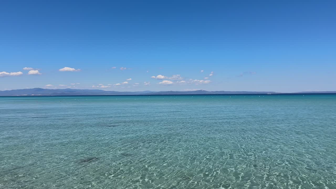 Stunning beach scene in Halkidiki, Greece, with elegant sunbeds facing the crystal-clear turquoise sea. A perfect summer escape in the heart of the Aegean.