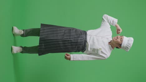 full body of asian man chef smiling and flexing his bicep while standing in the green screen background studio