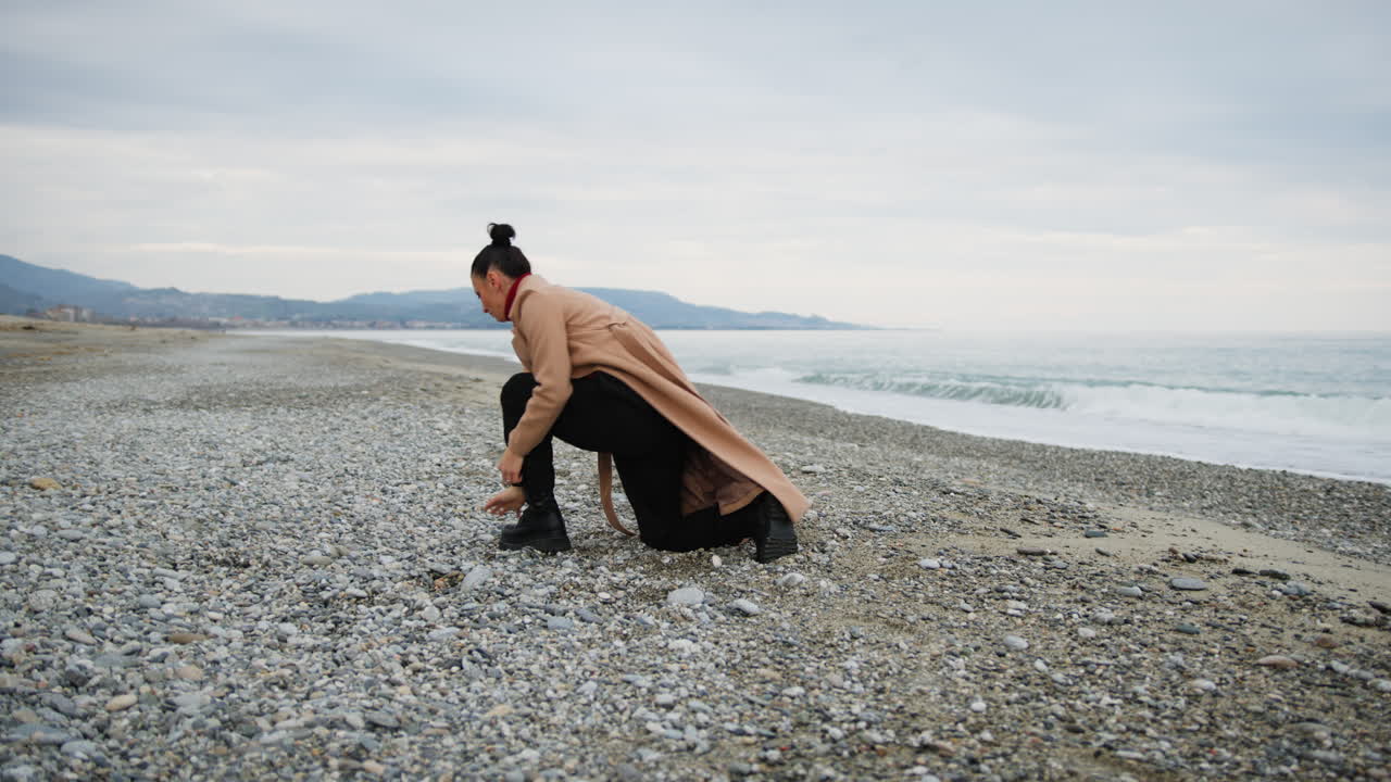 Woman Shows Artistic Dance Moves In Winter Coat On Coast Near Sea