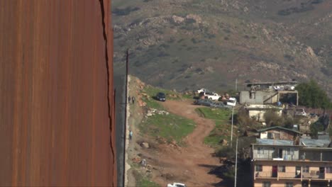 plano medio, gente caminando junto a la barrera fronteriza.