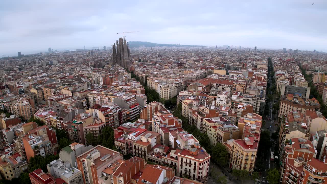 una toma aérea de la ciudad de barcelona y una formación triangular de una calle hacia la catedral de la sagrada familia