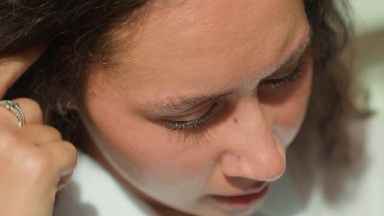 Latina woman island tearful closeup, emotional portrait with wet lashes and furrowed brow, hand touching ear and visible ring, raw sadness and quiet resilience, student or traveler wrestling