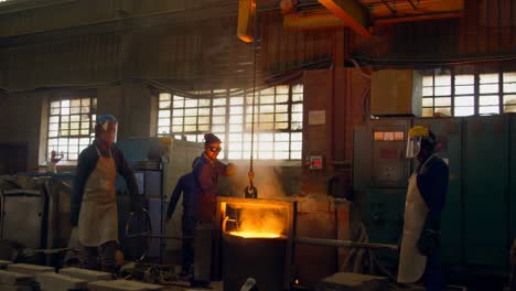 group of workers pouring molten metal in mold at workshop 4k