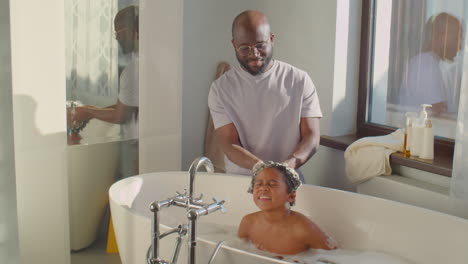 african american dad bathing little son at home
