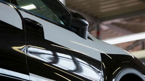 close-up of a sleek black car in a well-lit garage, highlighting the modern design and shiny finish