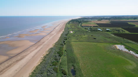 Aerial-footage-captures-the-charm-of-a-sunset-in-Skegness,-a-quaint-seaside-town-in-the-UK,-highlighting-the-town,-promenade,-pier,-and-the-scenic-coastline