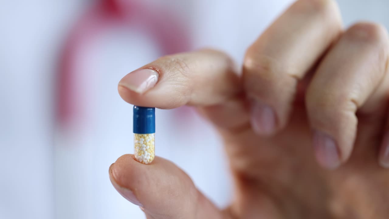 Medico che tiene in mano una capsula di medicinale, filmato 4K al rallentatore.