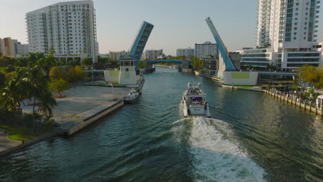 Luxury-boat-on-cruise-through-city.-Forwards-tracking-of-yacht-approaching-bridges-over-river.-Miami,-USA