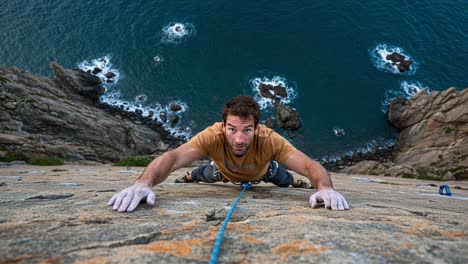 a daring ascent: harnessing strength and focus on a vertical rock face by the ocean's edge, showcasing the thrill of outdoor climbing and adventure sports