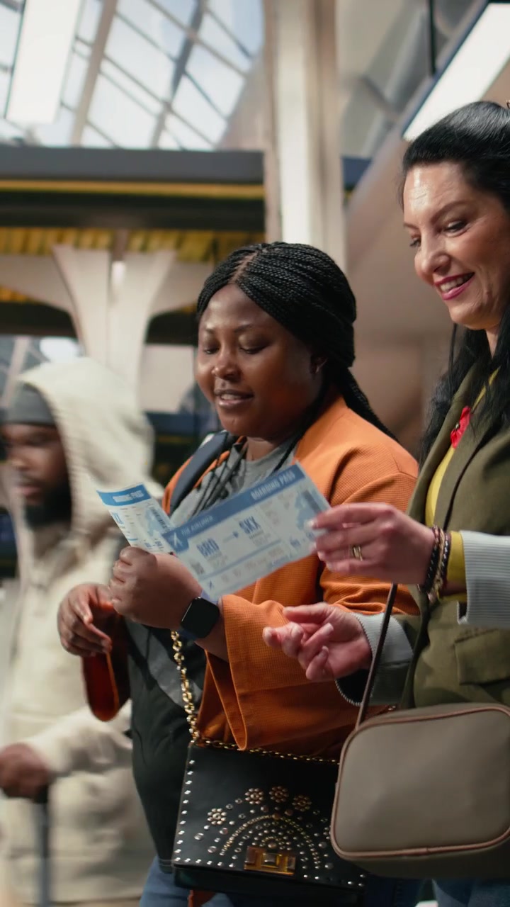 Vertical video Friends analyzing bus ticket details and smartphone navigation app while walking