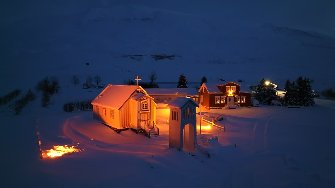 iglesia iluminada de naranja en un grueso paquete de nieve en islandia por la noche