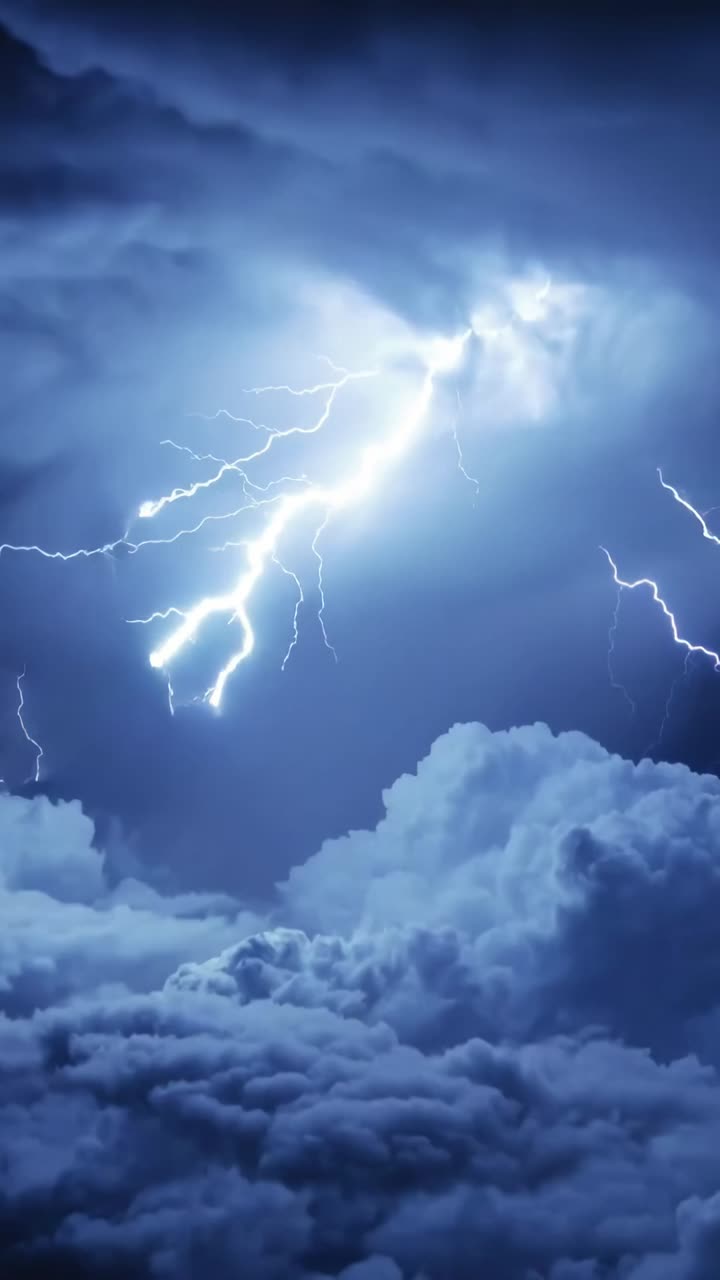 Video verticale: Campo di nuvole temporalesche che si illuminano per una scarica di notte, con fulmini ramificati.