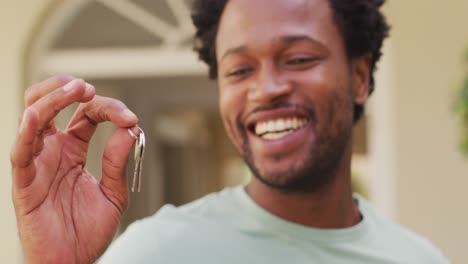 Portrait-of-happy-biracial-man-holding-keys-to-new-house