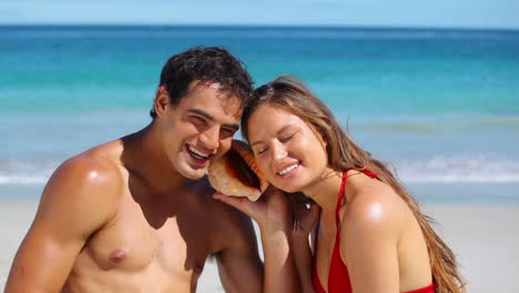 smiling couple listening to a seashell