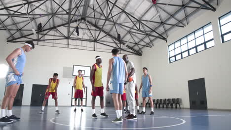 basketball players strategizing with coach during practice in school gym