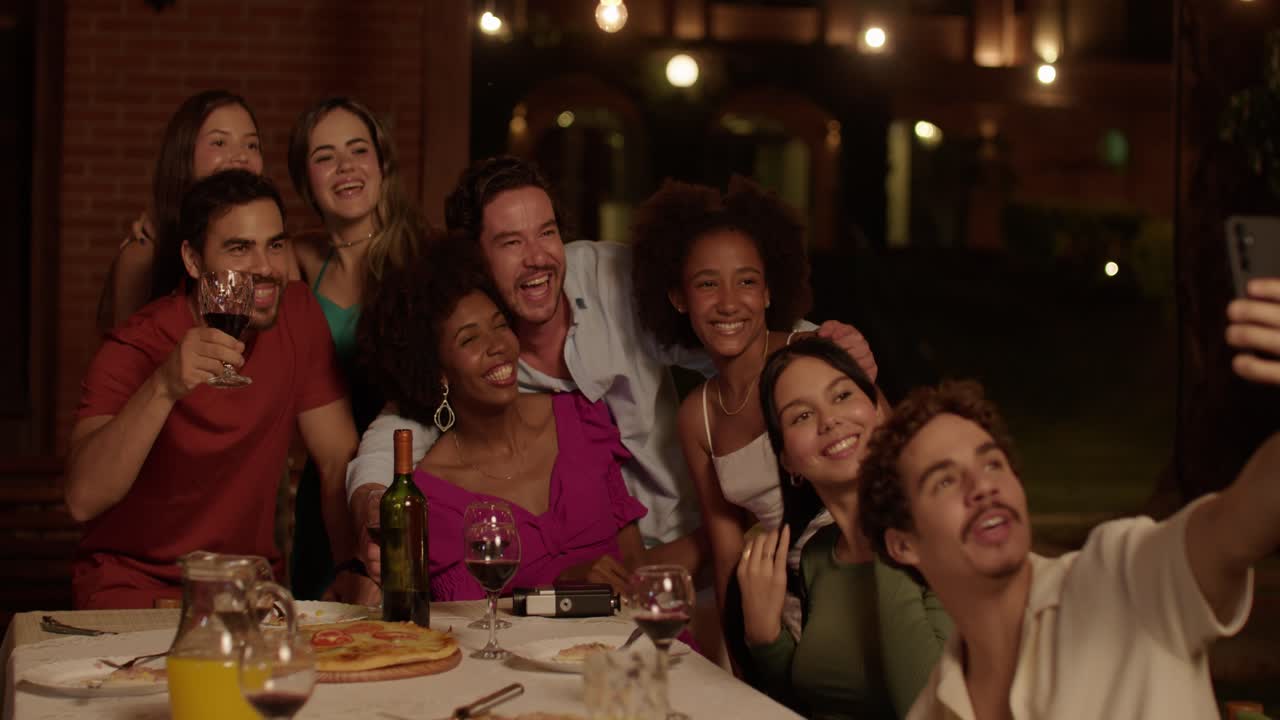 Friends laughing and taking selfies at a festive dinner party