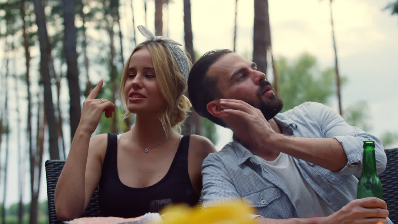 Beautiful couple spending time with friends on backyard. Guy listening to woman