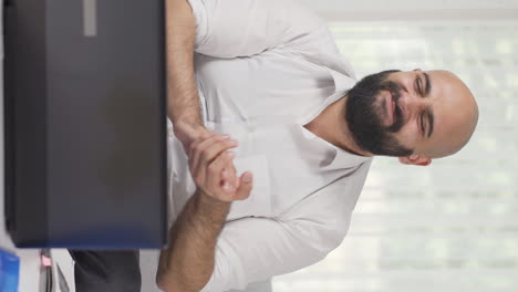 video vertical de un trabajador de oficina en casa aplaudiendo lo que ve en la computadora portátil.