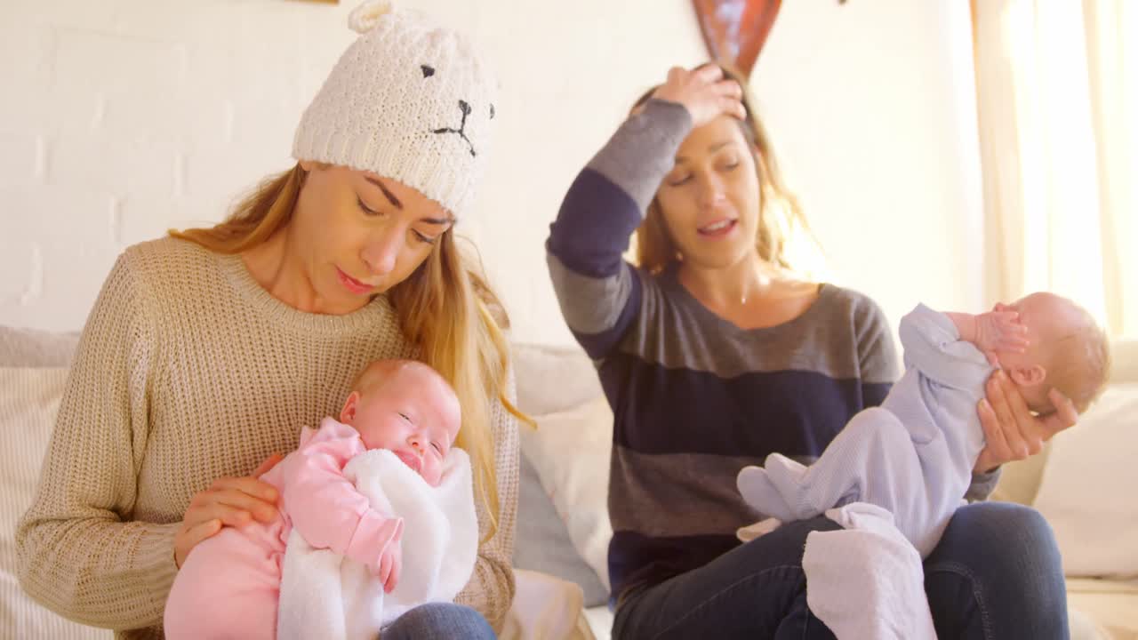 레즈비언 커플이 거실 4k에서 아기를 위로하고 있습니다.