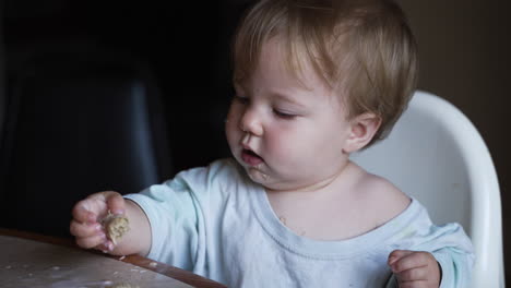 linda niña con ojos azules desayunando en una trona