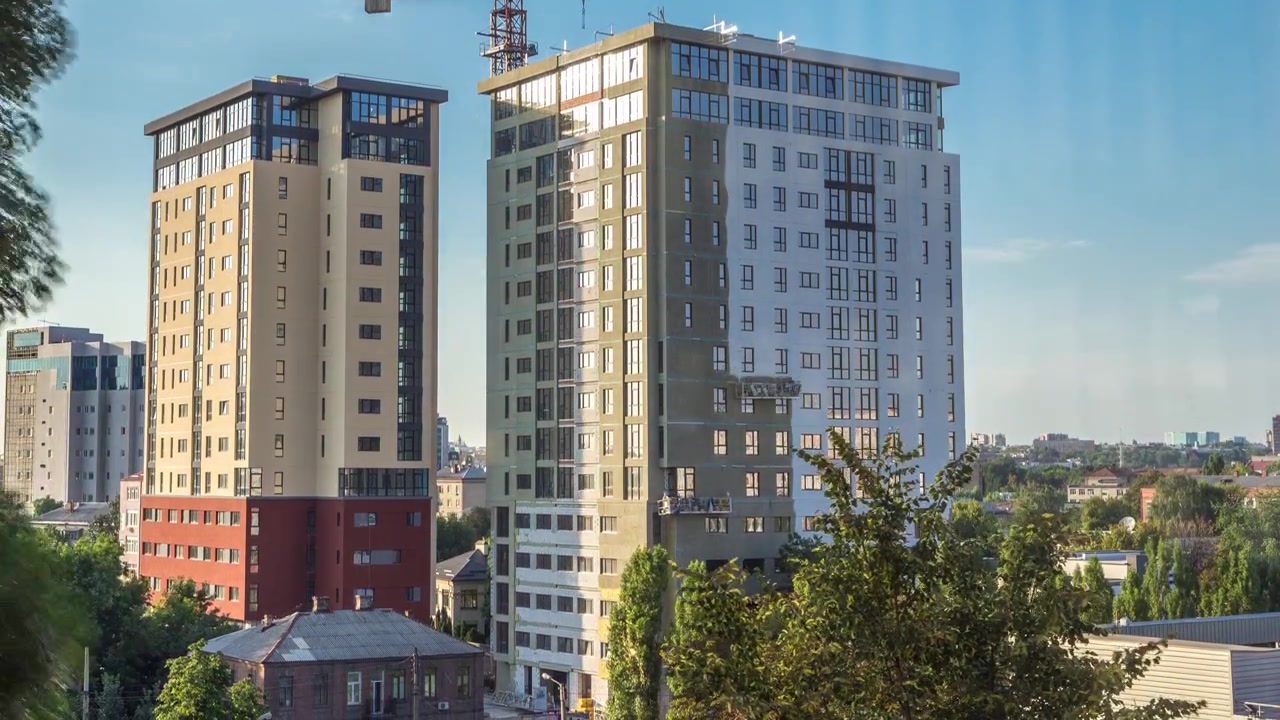 Guindaste e canteiro de obras contra o céu azul em timelapse aéreo. Trabalhadores pintando paredes de novo edifício residencial de apartamentos