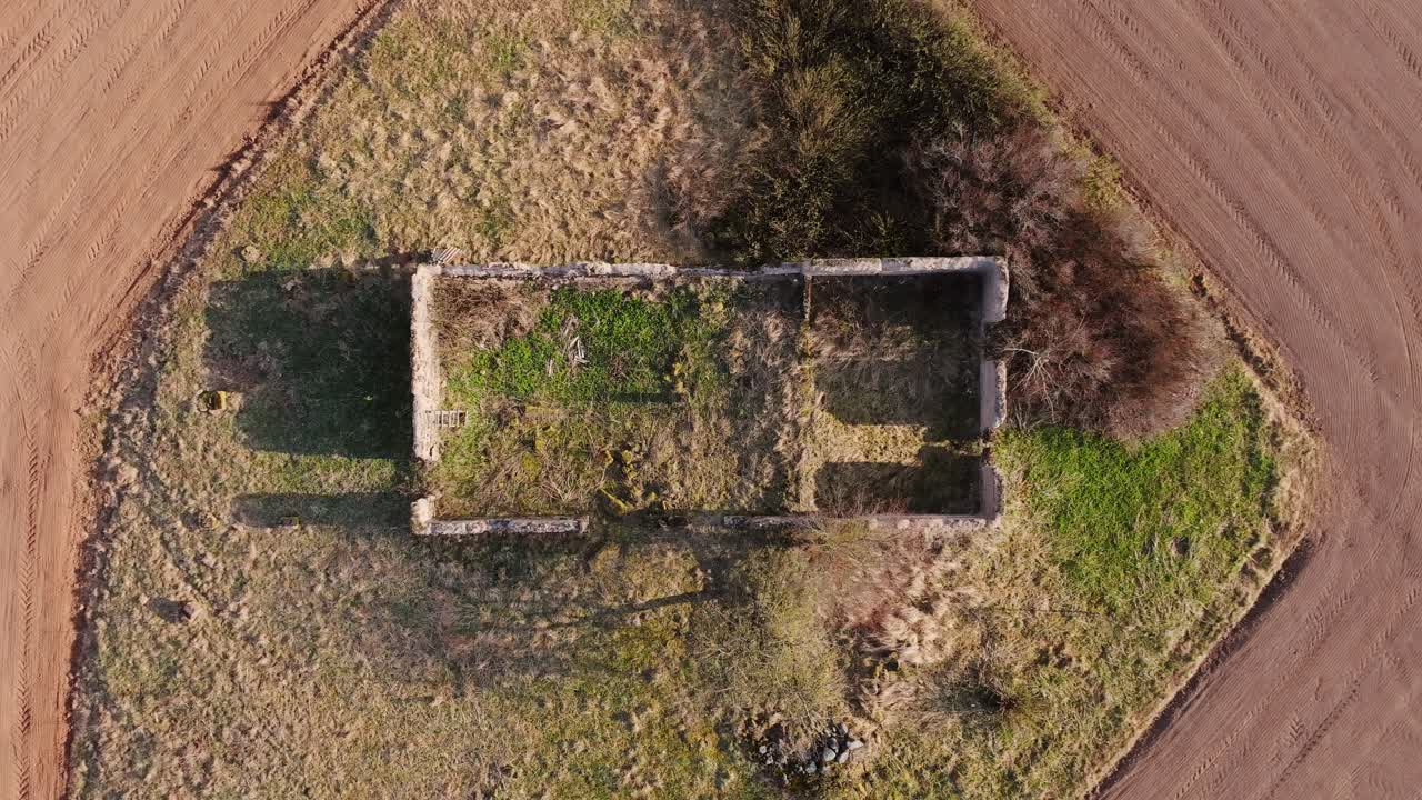 Empty stone wall remnants, spring greenery, brown farmland soil, Northern Europe