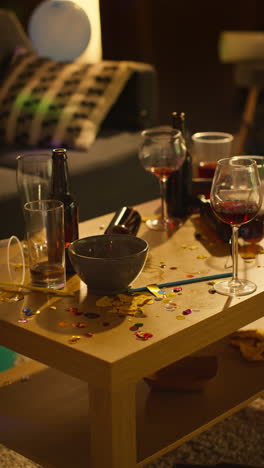 vertical video of messy table covered with empty wine glasses with beer bottles and snacks after house party