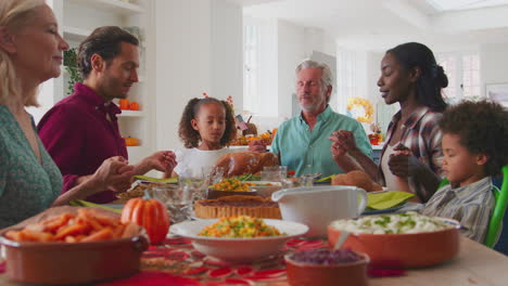 Multi-Generation-Family-Celebrating-Thanksgiving-At-Home-Saying-Prayer-Before-Eating-Meal-Together