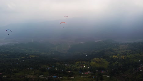 three paragliders fly over the nepali landscape