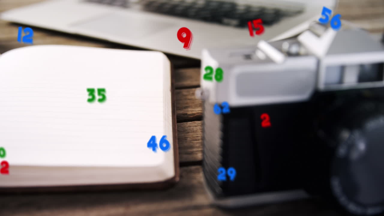 Animation of numbers changing over close up of desk with camera and laptop