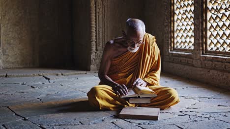 elderly buddhist monk reading in a temple