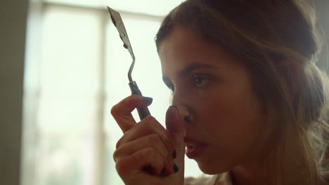 serious woman working in art studio. talented painter touching nose indoors.