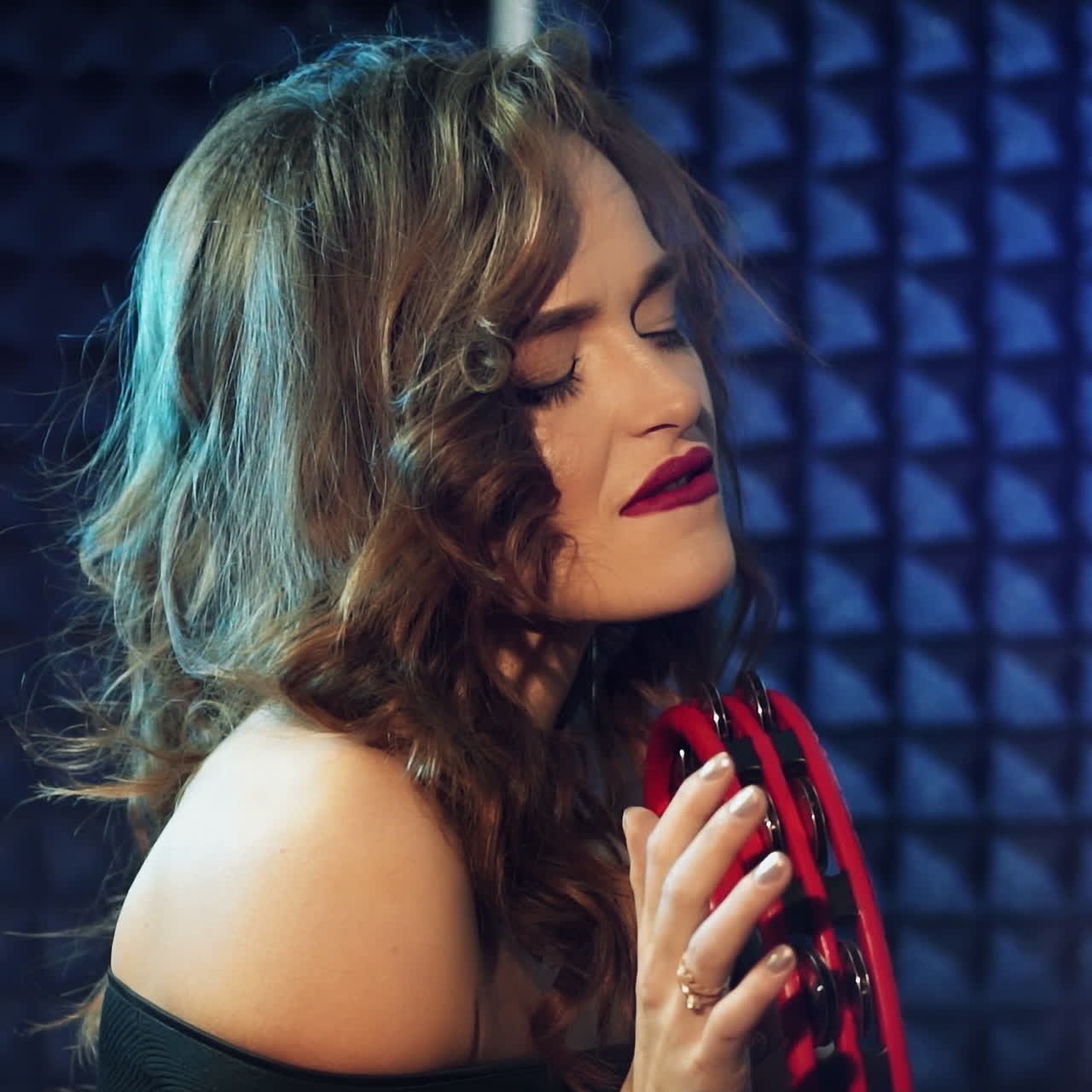 Woman playing a tambourine in a professional recording studio. Square video